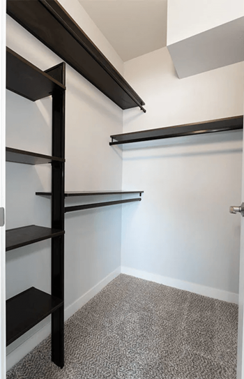A walk in closet with empty shelves and a white wall
